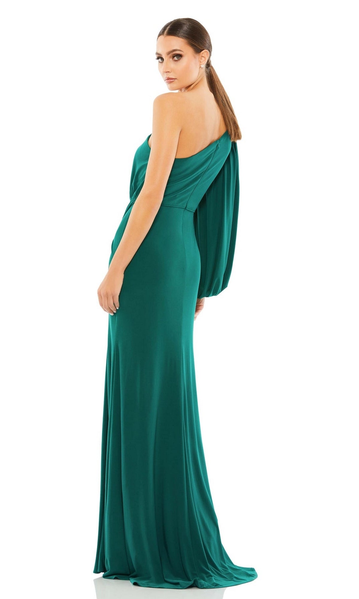 A woman with straight brown hair, seen from the back, wears the floor-length, emerald green Mac Duggal 67879 asymmetrical long formal dress featuring one sleeve.